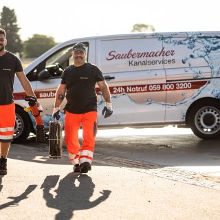 Zwei Mitarbeiter von Saubermacher Kanalservices tragen Spezialausrüstung für die professionelle Kanalreinigung vor einem Servicefahrzeug. © 2021, Saubermacher_Majland