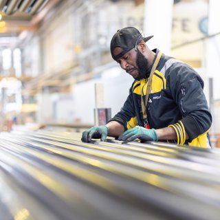 Mitarbeiter prüft lange Metallprofile in einer modernen Produktionshalle von Kärcher © wienerberger AG