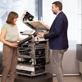 Judit Göndöcs und ein Kollege im Gespräch über Druckerkomponenten im Rahmen der Saubermacher-Partnerschaft (c)2025, Saubermacher