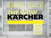 Eingangsbereich eines Kärcher Centers mit großer Glasfassade und gelbem Schriftzug „Bring back the WOW“ – sichtbares Branding als Teil der Unternehmensidentität. (c) 2025, Saubermacher, Antal