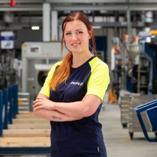 Mitarbeiterin mit verschränkten Armen in einer modernen Produktionshalle von Kärcher © Bianca Gadnik