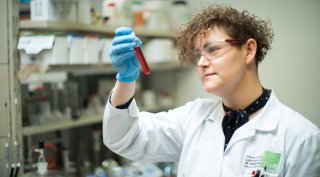 Chemische Analyse im Umweltlabor © Saubermacher/kump.photography Laborfachkraft mit Schutzbrille und blauen Handschuhen prüft ein Reagenzglas mit roter Flüssigkeit bei einer chemischen Analyse im Umweltlabor. © Saubermacher/kump.photography