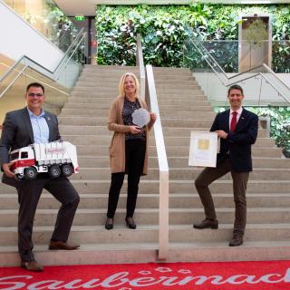 Saubermacher als Arbeitgeber dreifach ausgezeichnet Harald Gorucan, Annemarie Gräßler und Vorstandsvorsitzender Ralf Mittermayr mit dem Staatspreis Familie an der Stiege des Saubermacher Ecoports.