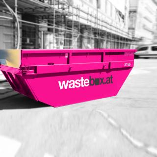 Die pinke Wastebox Mulde vor einer Baustelle